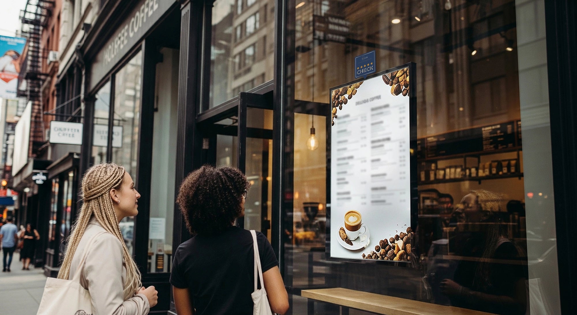 Two women walking past a coffee shop with a digital poster display menu displaying coffee options.